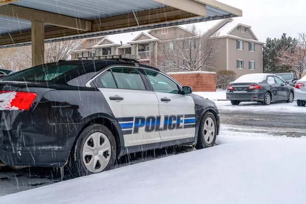 Black and white police car parked in the neighborhood on a snowy and rainy day — Stock Photo, Image