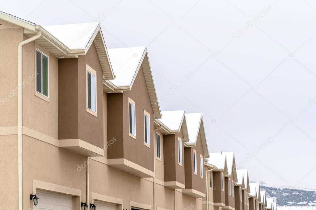 Focus on upper floors of two storey townhouses against white sky view in winter