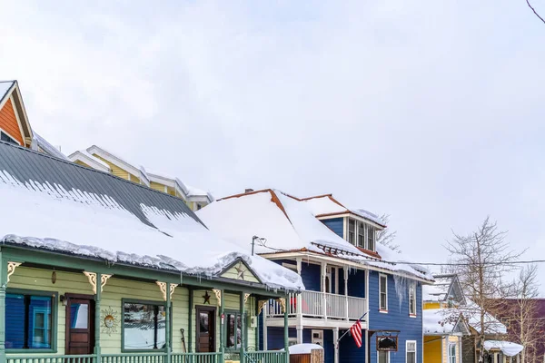 Fasada domów z drewnianymi ścianami zewnętrznymi i dachami śnieżnymi z lodem — Zdjęcie stockowe