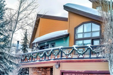 Yarım yamalak çatıları ve kışın karla kaplı balkonları olan ev cephesi