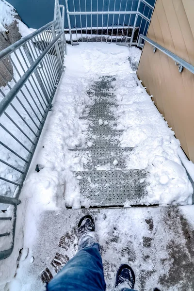 Nohy člověka na schodišti po straně budovy pokryté sněhem v zimě — Stock fotografie