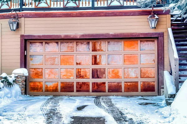 Panelled metal garage door of home beside stairs that leads up to snowy balcony — Stock Photo, Image