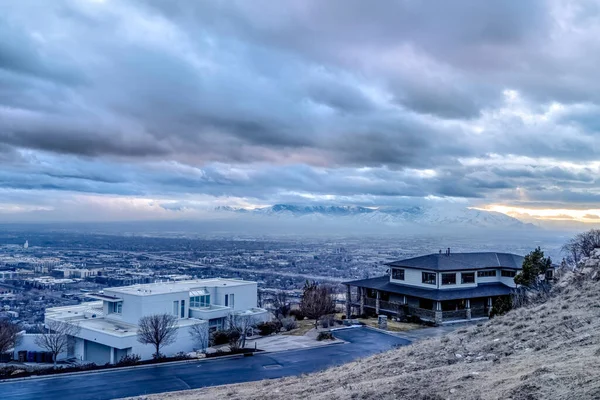 Casas de lujo en una colina con vistas a la montaña nevada y cielo nublado en invierno — Foto de Stock