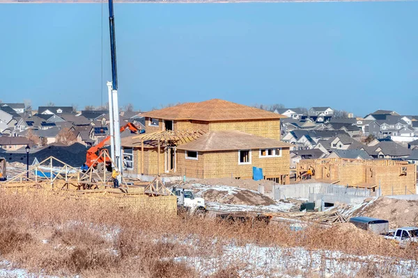 Maison en construction dans un quartier enneigé avec ciel nuageux en hiver — Photo