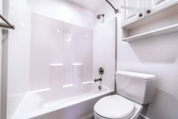 Toilet and built in bathtub in side residential bathroom with clean white wall — Stock Photo, Image