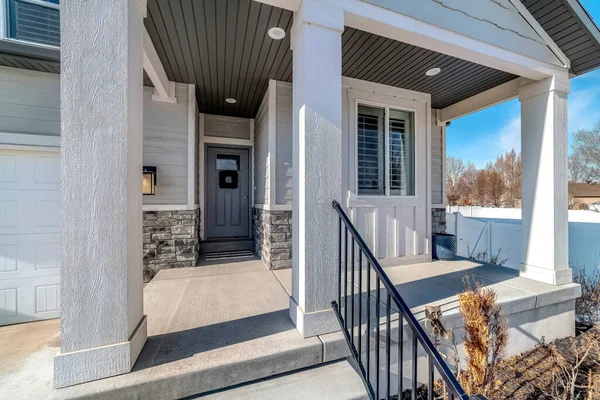 Vista frontal de una hermosa casa con escaleras y porche frente a la puerta principal gris — Foto de Stock