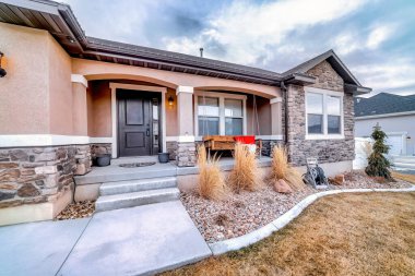 Bahçeye bakan beton verandalı ve asfalt yollu bir ev.