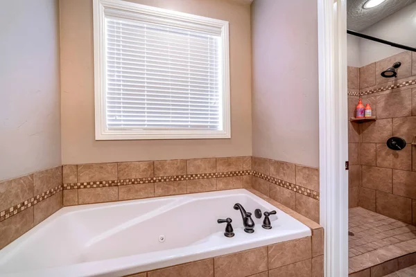 Built in bathtub and shower stall inside bathroom of home with brown tiles — Stock Photo, Image