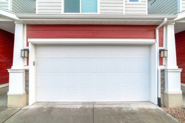 Garajın dış tarafını, duvar lambaları arasında beyaz panelli kapıyla kapatın.