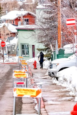 Yol kenarında barikatlarla yürüyen ve park levhası olmayan bir kadın.