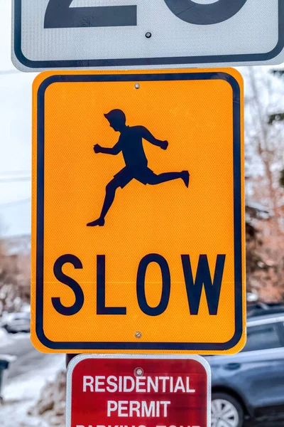 Close up of bright yellow Slow road sign with silhouetted image of running man — Stock Photo, Image