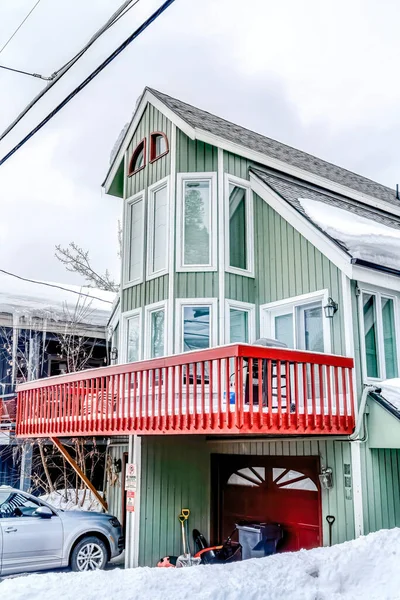 Koyun pencereleri balkon ve evin önündeki kırmızı garaj kapısı bulutlu gökyüzüne karşı.