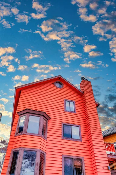 Home with red exterior wall bay windows and sliding windows against cloudy sky