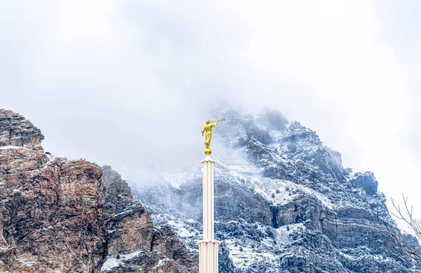 Věž kostela se zlatou sochou proti horské krajině a zamračené obloze — Stock fotografie