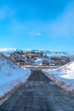 Vadi dağına ve mavi gökyüzüne bakan evleri olan bir yol.