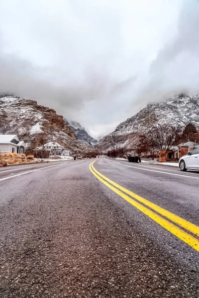 Carretera a lo largo de casas y edificios en una ciudad pintoresca con vistas nevadas a la montaña — Foto de Stock