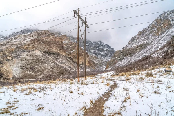 Poteaux électriques sur une colline avec des sentiers étroits et couverts de neige en hiver — Photo