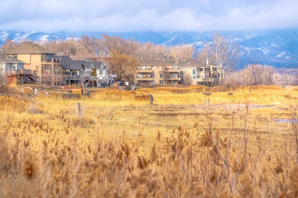 Enorme terreno con hierbas marrones contra las casas y la montaña en el fondo — Foto de Stock