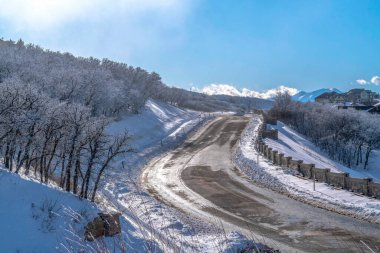 Güneşli bir günde mavi gökyüzüne bakan kışın karlı manzaralı dağda yol