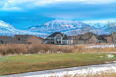 Görkemli dağ geçmişine sahip evlerin önünde patikası olan otlak bir arazi.