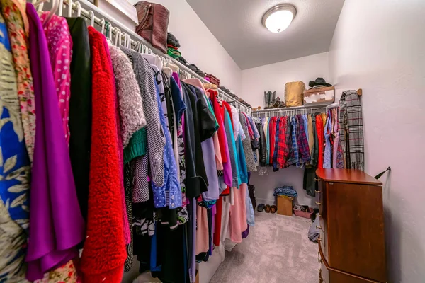 Walk in closet interior con ropa de colores colgando de varillas contra la pared blanca — Foto de Stock