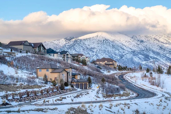 Casas y camino en una ciudad de montaña con vistas a picos nevados y cielo nublado —  Fotos de Stock