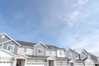 Banliyödeki evlerin ön cephesinde girişler ve beyaz garaj kapıları.