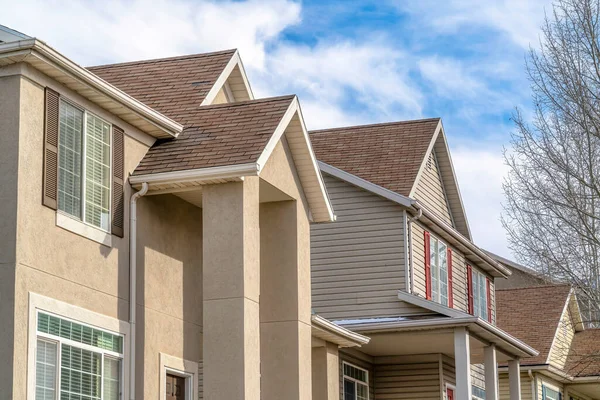 Casas con techos a dos aguas y paredes exteriores de color beige contra cielo azul y nubes — Foto de Stock