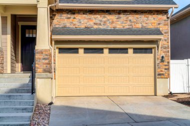 Camlı ön kapı ve evin geniş garaj kapısı. Garaj yolu ve merdivenleri var.