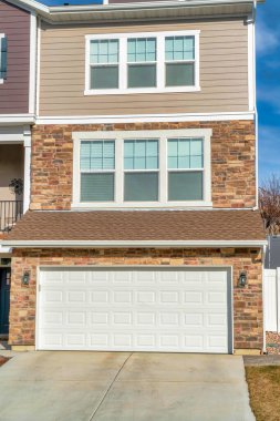 Geniş beyaz garaj kapısı olan üç katlı bir binanın garaj cephesi.