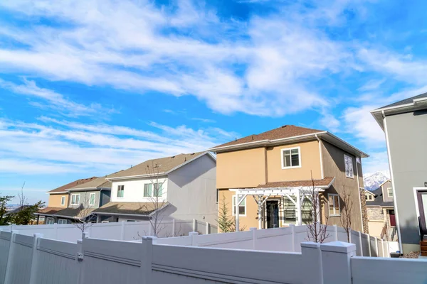 Casas de dos pisos con vallas de madera blanca debajo de nubes brillantes y cielo azul — Foto de Stock