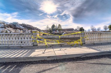 Çitle çevrili boş arazi ve karlı dağa karşı sarı uyarı bandı.