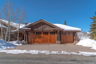 Park City Utah 'ta cam camlı, kahverengi ahşap garaj kapısı olan dağ evi.