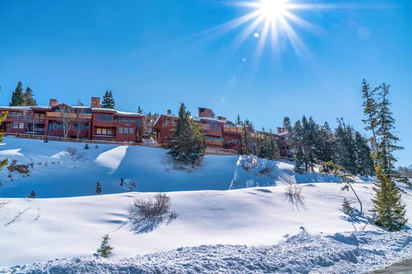 Sol brilhante e céu azul sobre casas na colina com cobertura profunda de neve no inverno — Fotografia de Stock
