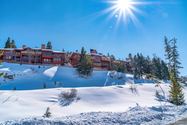 Bright sun and blue sky over homes on hill with deep covering of snow in winter — Stock Photo, Image