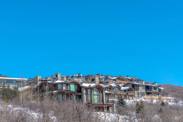 Maisons luxueuses dans un cadre montagneux pittoresque contre un ciel bleu clair en hiver — Photo