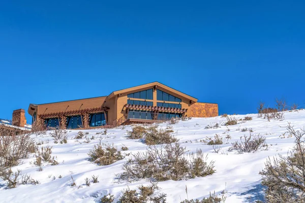 Mountain covered with snow in winter with a beautiful brown home at the top — Stock Photo, Image