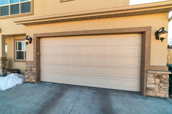 Duvarların arasında geniş beyaz panelli kapısı olan bir evin garajı.
