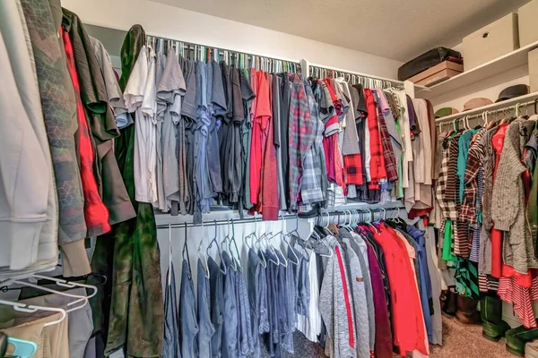 Residential walk in closet interior with colorful clothes hanging on metal rods