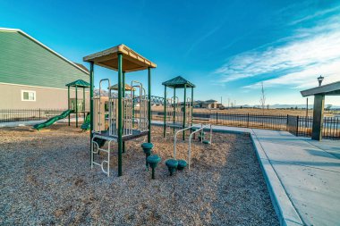 Güneşli mahallede çocuklar için oyun alanı. Evlere ve mavi gökyüzüne bakıyor.