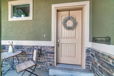 Klasik sundurma masası ve evin ön kapısı çelenkle süslenmiş sandalyesi.