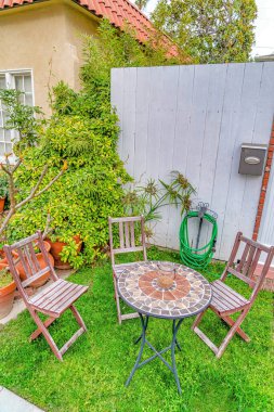 Long Beach California 'da bir ev. Masası ve ahşap çitlere yaslanmış sandalyeleri var.