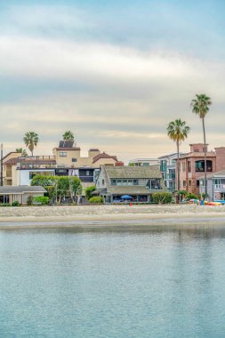 Güzel rıhtım evleri ve bulutlu gökyüzüne karşı palmiye ağaçları olan sahil.