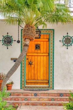 Long Beach California 'da dekoratif fayanslarla çerçevelenmiş kahverengi ahşap ön kapı.
