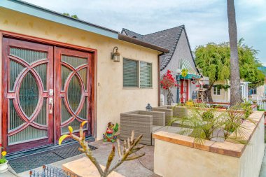 Evin ön kapısı cam camlı, verandada şezlonglar var.