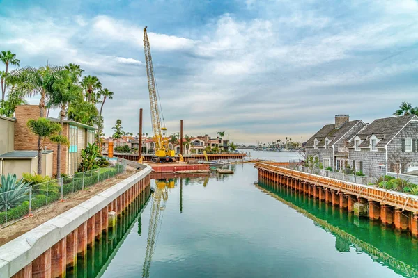 Żółty żuraw w doku przy kanale z domami nad brzegiem morza w Long Beach California — Zdjęcie stockowe