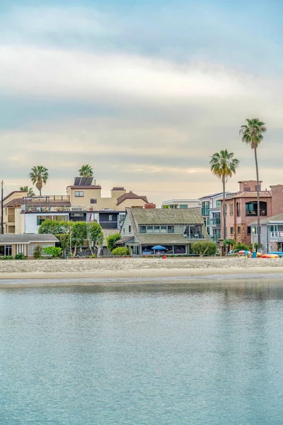 Strand met prachtige huizen aan het water en palmbomen tegen bewolkte skyscape — Stockfoto