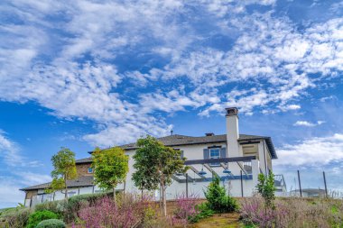 Cloudy blue sky with contrail over modern home in Huntington Beach California