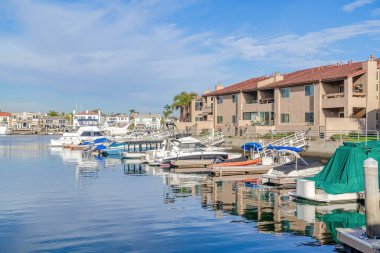 Boats docked at the harbour with waterfront homes in Huntington Beach California