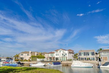 Serene blue sky over houses overlooking boats at the harbor in Huntington Beach